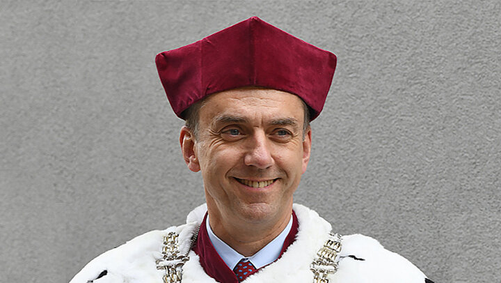 Mężczyzna w bordowym birecie i todze z kołnierzem z gronostajów