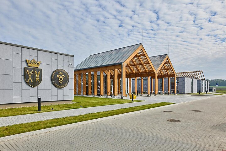 Nowoczesny kmpleks budynków łączących regularne bryły z drewnanymu szkielatami nawiązującymi do lasyczej bryły stodoły.