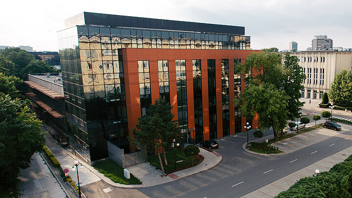 Zdjęcie elewacji nowoczesnego budynku. Sciane szklany zdobią pionowe elementy w kolorze cegły.